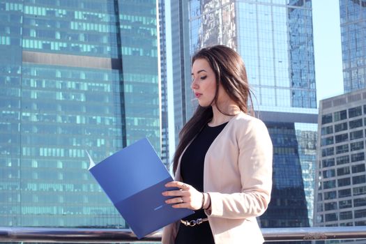 Young beautiful businesswoman outdoors at skyscraper background