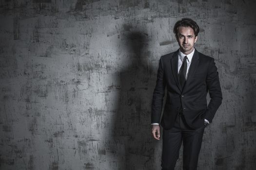 Portrait of a pensive businessman in suit over concrete wall background