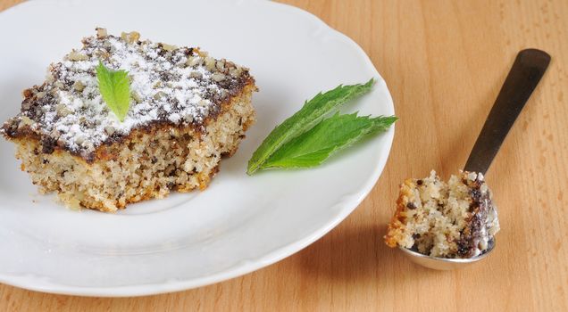 Sweet cake (gingerbread) with chocolate icing, nuts and small mint leaf.