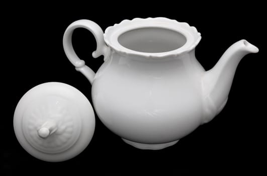 White porcelain teapot placed on the black background.