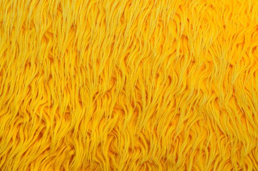 Closeup image of yellow shaggy carpet.