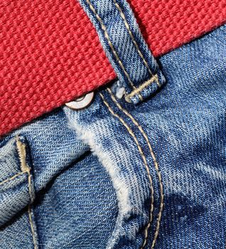 Macro shoot of jeans pocket and red belt.