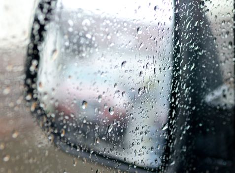 View to the rear mirror covered by water from rain.