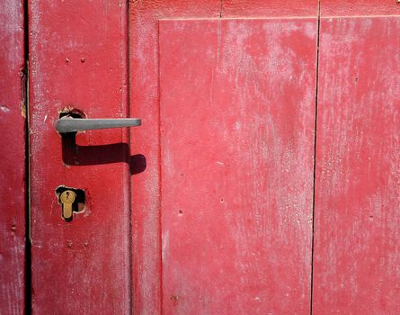 Part of old red wooden door with metal handle.