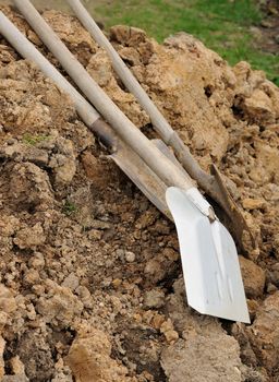 Shovel and spades placed on the big soil heap.