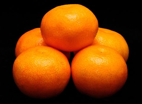 Stack of mandarines placed on the black background.