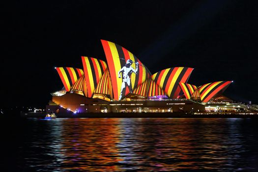 SYDNEY, AUSTRALIA - MAY 29, 2016;  Sydney Opera House in moving colour of patterns, shapes and lines during the Vivid Sydney Annual Event.  Displaying red yellow black stripes and aboriginal hunter with spear.