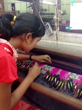 Mandalay, Myanmar - April 21, 2013 : Young Burmese women weaving cotton in a silk and cotton factory