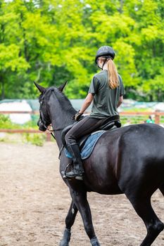 girl sportsman rides on horse training outdoors