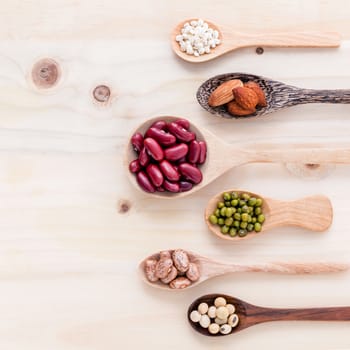 Assortment of beans and lentils in wooden spoon on wooden background. mung bean, groundnut, soybean, red kidney bean and almond.
