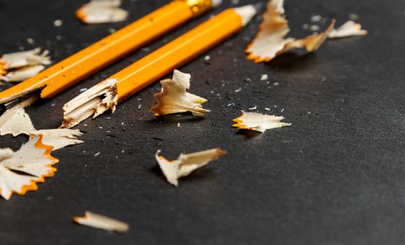 Broken pencil with shavings on black background. Horizontal image.