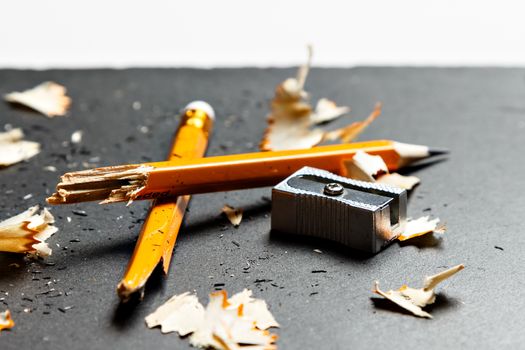 Broken pencil with metal sharpener and shavings on black background. Horizontal image.
