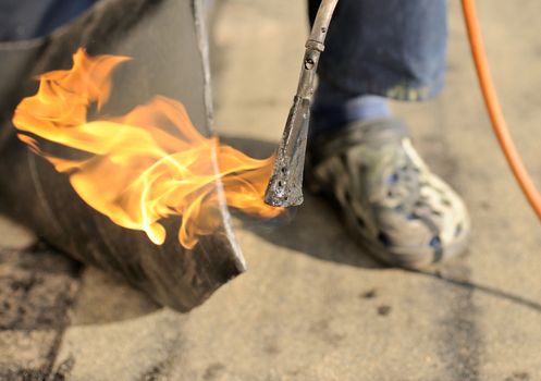 Man working with burner and insulation on the roof.