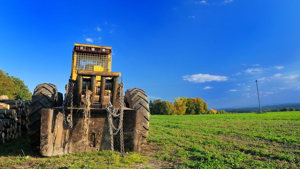 Old yellow digger parked on the field.