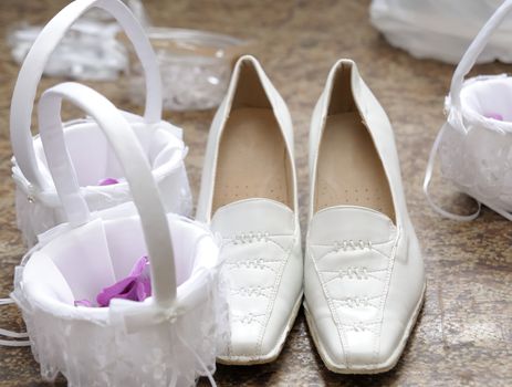 Bridal shoes and small baskets with purple blossoms.