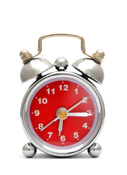 Old metal alarm clock with red dial on the white background.