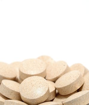 Macro shot of brown tablets on a white background.