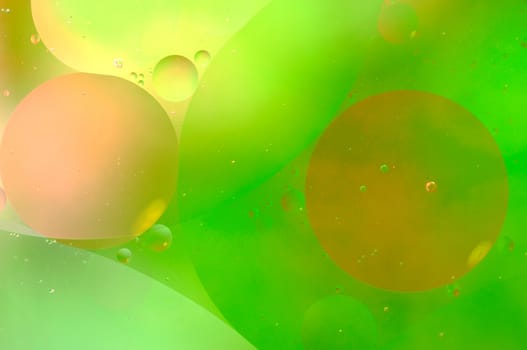 Abstract green background from floating oil bubbles in the water.