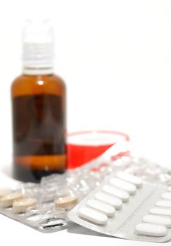 Small tablets and other medicaments on a white background.