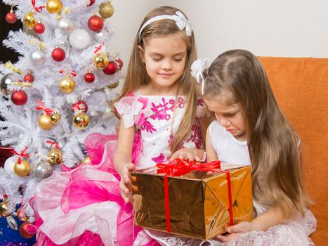 The older girl gives younger unwanted gift
