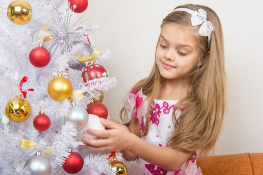 Seven-year girl in a beautiful dress treats Christmas toys