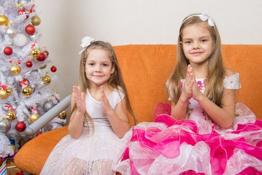 Two girls in beautiful dresses guessing gifts for the new year