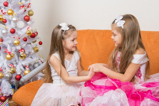 Two girls in beautiful dresses waiting Gift joined hands