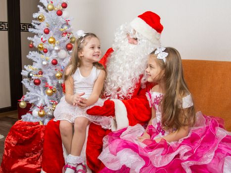 Little girl sitting on the lap of Santa Claus and tells poem