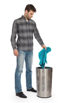 Young man putting a dirty towel in a laundry basket, isolated