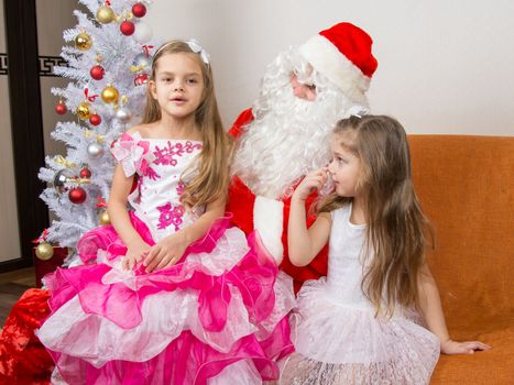 The older girl is sitting on the lap of Santa Claus and tells poem