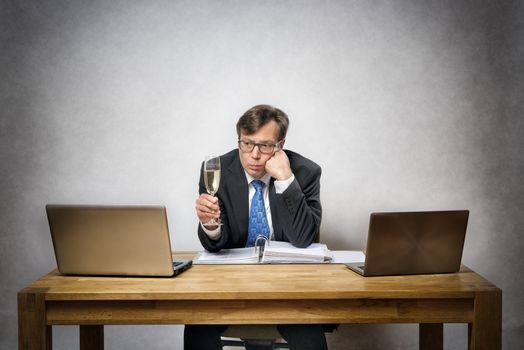 Image of frustrated lonely business man with champagne glass in office