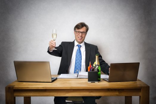 Image of happy business man with champagne glass in office