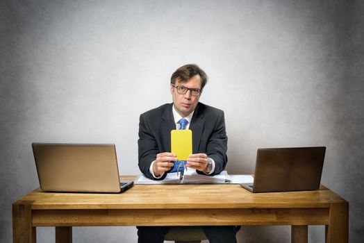 Image of business man with yellow card in office