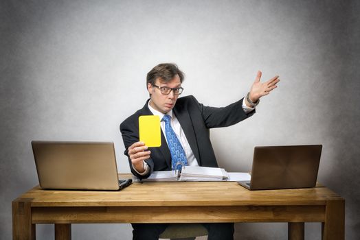 Image of business man with yellow card in office