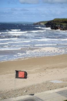 quicksilver flag flying beside surf school with ballybunionbeach and cliffs in background