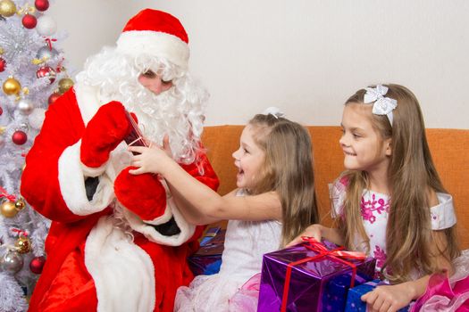 The Santa Claus gives presents two sisters
