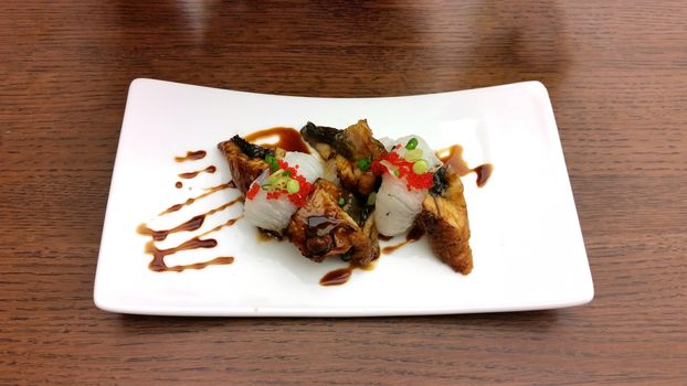 Engawa Unagi Nigiri Sushi Dish decorated with sweet source in white ceramic dish on wooden table