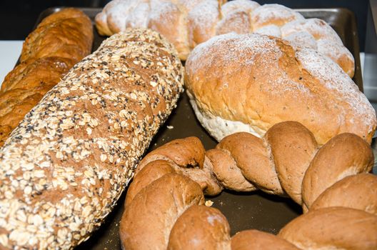 Many mixed breads and rolls on table.