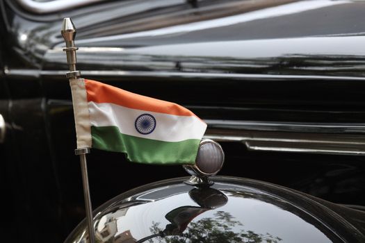 The tricolor Indian flag set on a very old black vintage car.