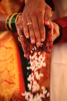 The hands of an Indian groom and bride performing a traditional wedding ritual.