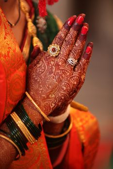 Folded henna decorated hands of an Indian bride during a prayer in a traditional Indian wedding