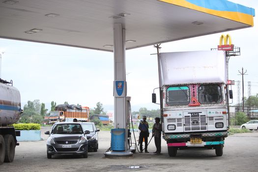 Cars and trucks filling petrol and diesel at a gas station in india.