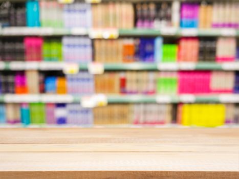 Perspective light wood over blurred colorful supermarket products on shelves - Shampoo bottles background - can be used for display or montage your products. Mock up for display of product