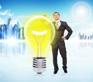 Idea concept with businessman and big light bulb on city background