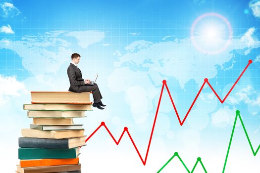 Businessman with laptop sitting on stack of books on blue sky background with chart