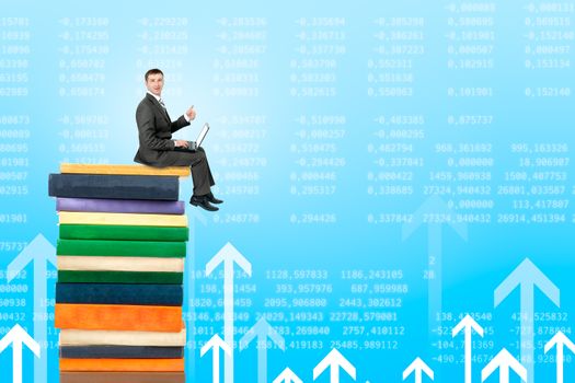 Businessman with laptop sitting on pile of books on graphical chart background