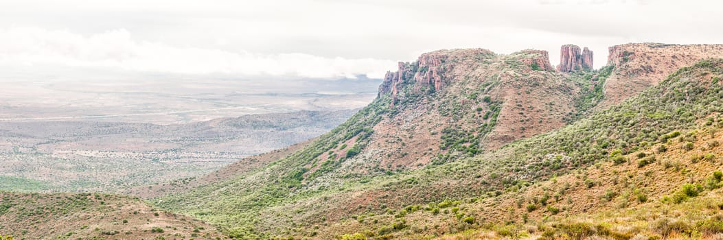 Rain is falling in a stitched panorama of dolerite columns with the Valley of Desolation below as seen from the road to viewpoint next to the columns near Graaff Reinet