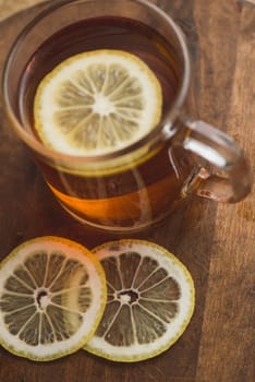 Top view of black tea with lemon in cup and on wooden plank table.