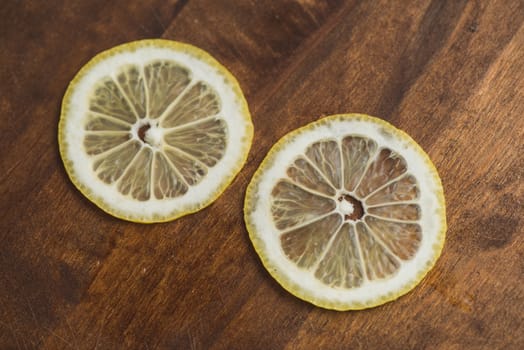 two thin slices Fresh Lemon on Wood Table Background, Rustic Style