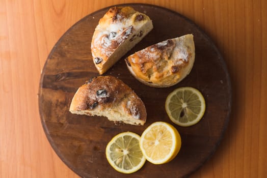 Top view of muffin with lemon in cup and on wooden plank table.